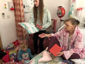 Woman opening presents on hospital bed
