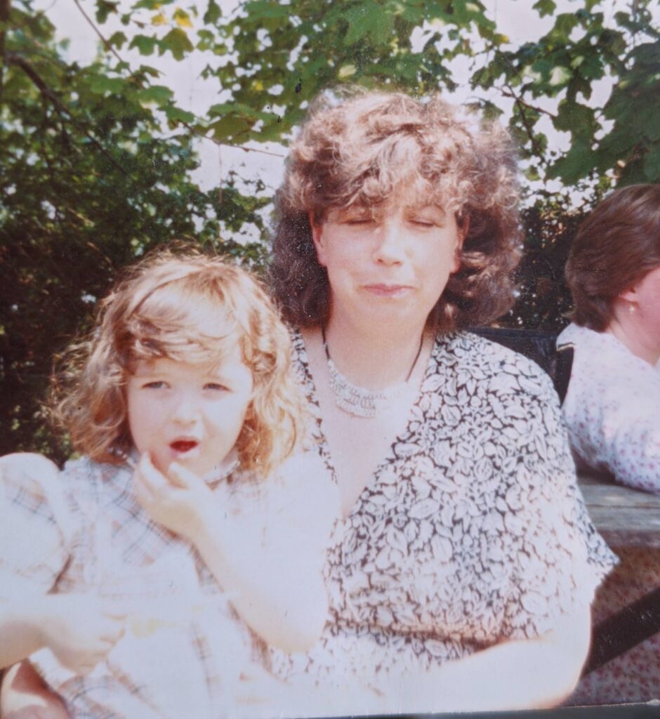 Dated photo of woman sitting with a little girl in front of a tree