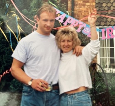 Man and woman posing in front of birthday banner