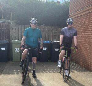 Two men on bikes look towards the camera