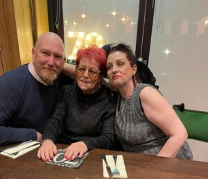A man and two women sat at a table smile at the camera