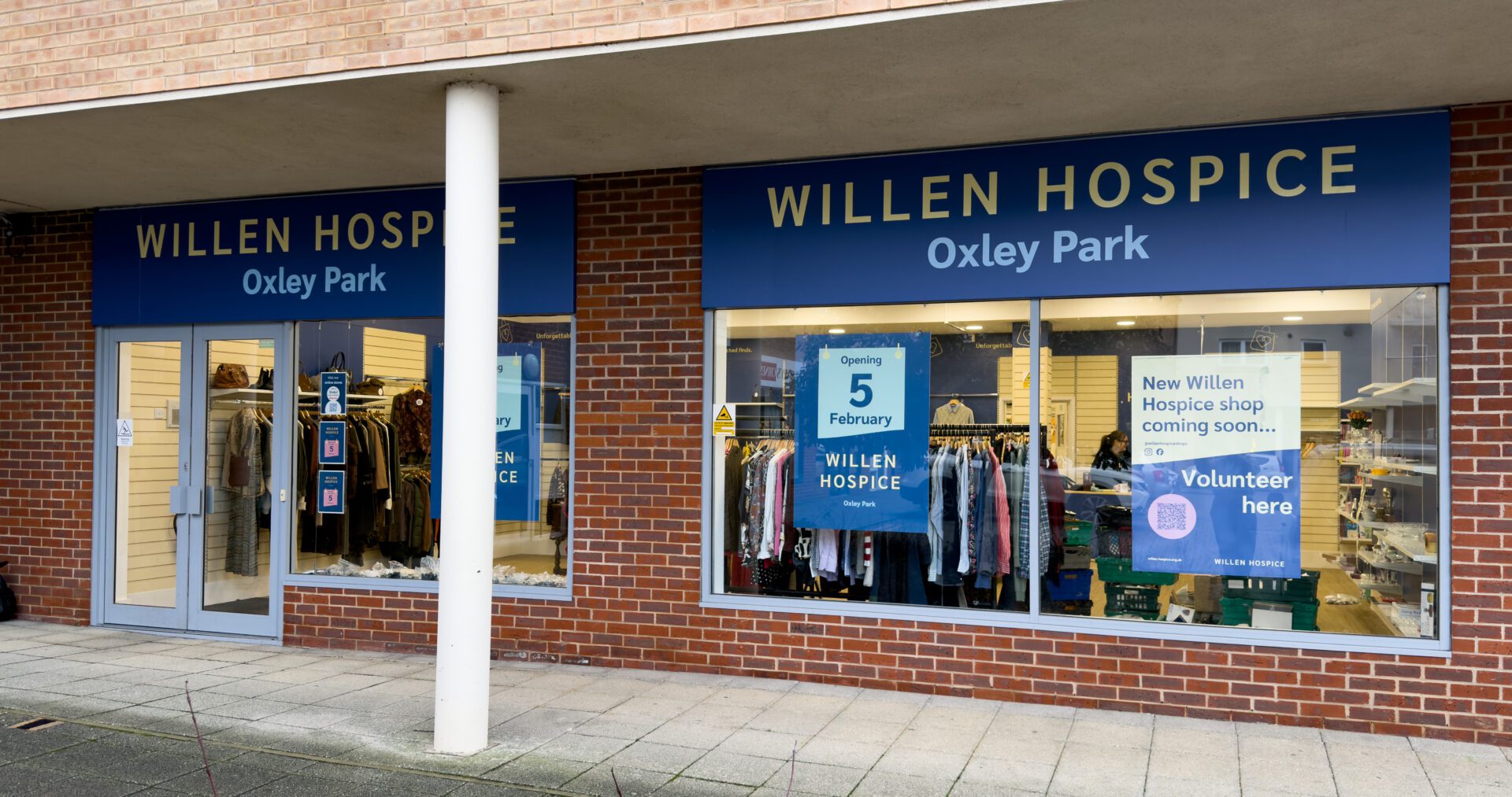 A shopfront in a brick building with a blue and yellow branding above the window.