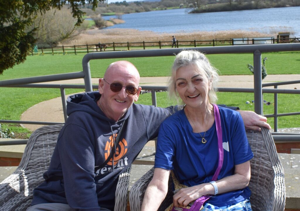Man and woman sitting outside smiling at camera