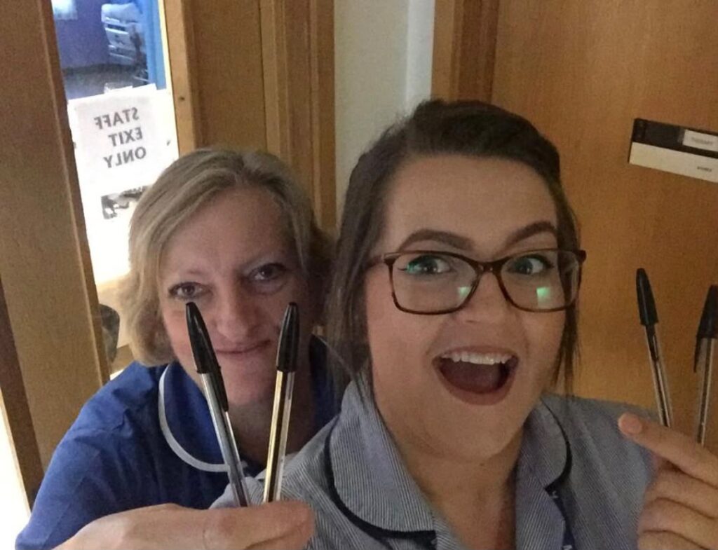 Two nurses in uniform smiling at camera