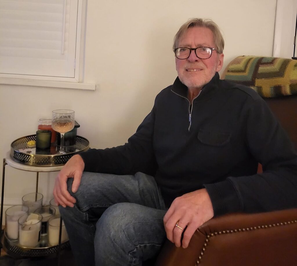 Man sitting in an armchair with a drink on a table close by