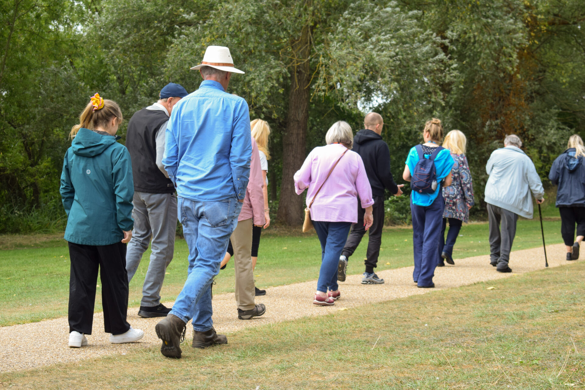 Group of people walking away from camera along a grassy path
